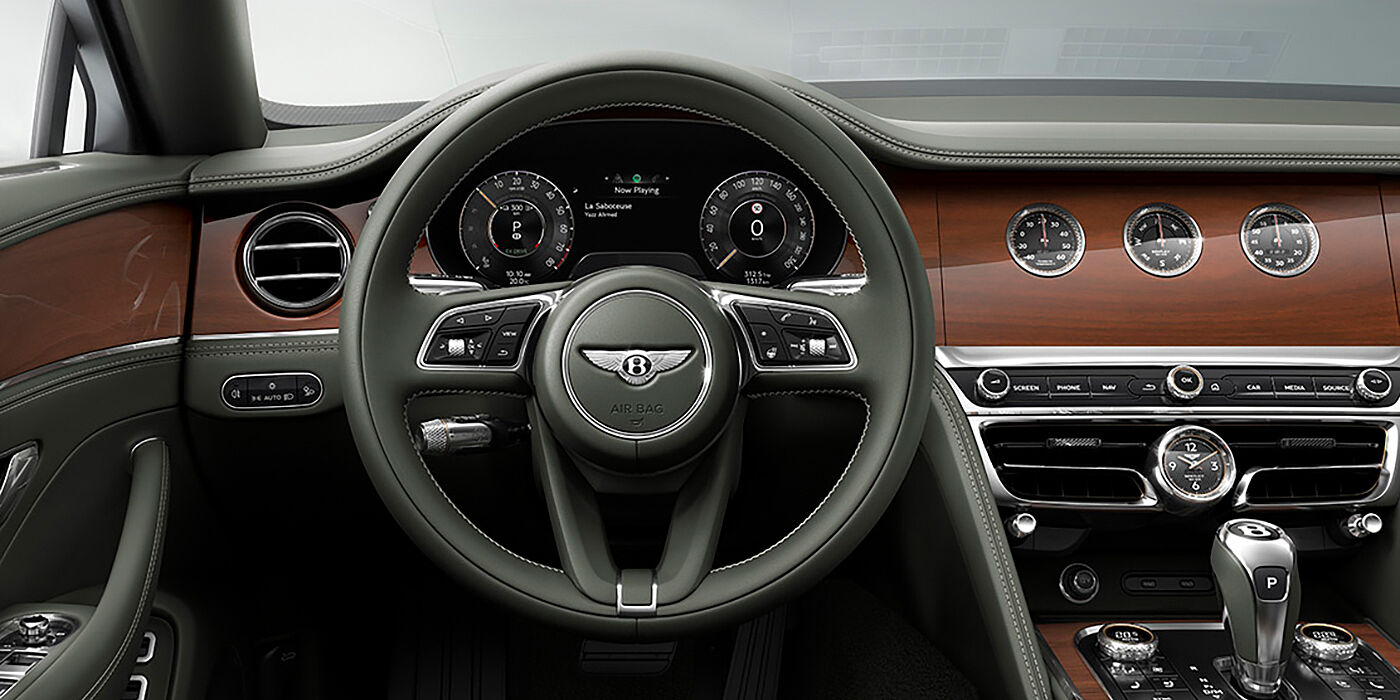 Bentley Tunbridge Wells New Bentley Flying Spur sedan front cabin in Cumbrian Green hide and Crown Cut walnut veneer showing steering wheel and Rotating Display with three clocks on face