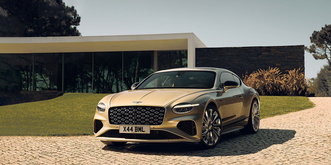 Bentley Tunbridge Wells Bentley Continental GT Mulliner coupe front three quarters in Patina paint parked outside a glass fronted building with a grass lawn behind it
