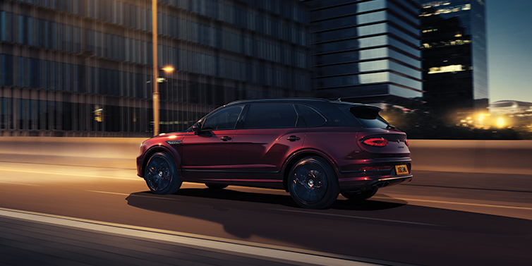 Bentley Tunbridge Wells Bentley Bentayga Extended Wheelbase Mulliner SUV in Cricket Ball red paint driving dynamically in city at night